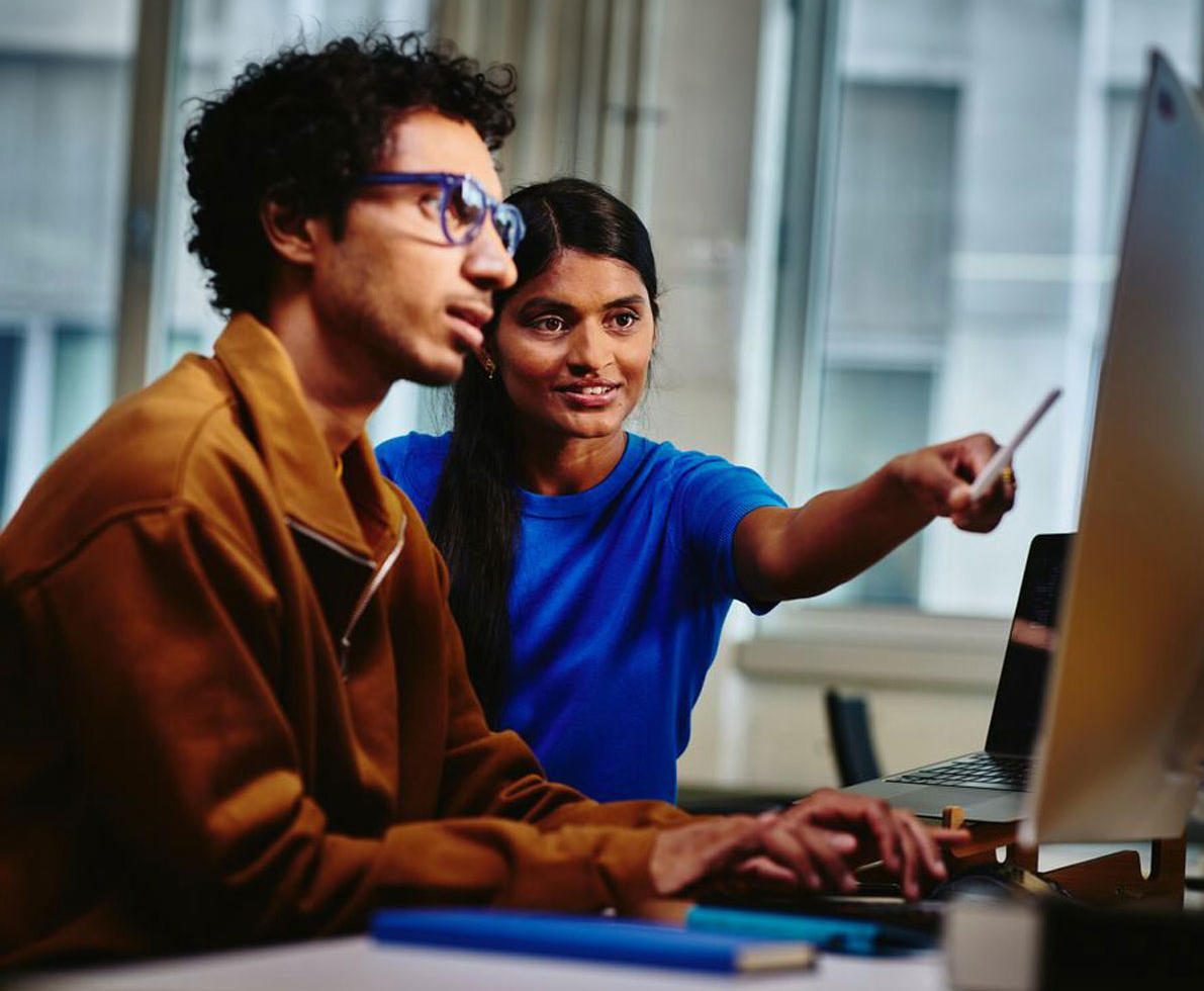 diverse coworker pointing to desktop screen