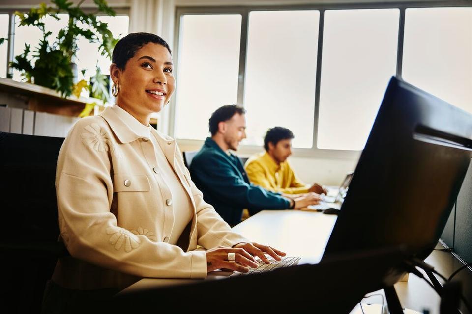 Woman working on her computer, sitting next to 2 other colleagues