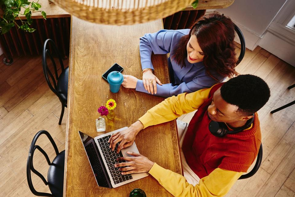 Bird view of a female and male working on a laptop at a table